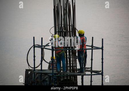 Guwahati, Inde. 27 mars 2023. Les ouvriers de la construction se sont occupés à fabriquer un poteau en béton près de la rivière Brahmaputra à Guwahati. Banque D'Images