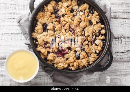 Tarte aux pommes et aux bleuets Smulpaj suédois servie avec une sauce à la vanille maison sur une table en bois. Vue horizontale du dessus Banque D'Images