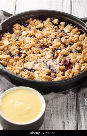 Tarte aux fruits suédois avec sauce à la vanille maison, à deux pas de la table en bois. Verticale Banque D'Images