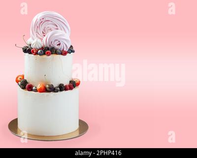 Gâteau au chocolat, tourbillons de meringue et cupcakes aux couleurs vives et hautes. Isolé sur fond rose avec un espace de copie sur un côté. Horizontale Banque D'Images