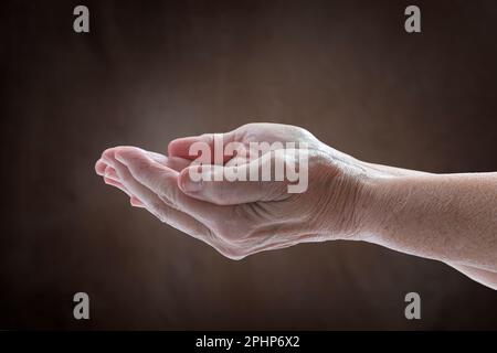 Prise de vue horizontale des mains d’une femme âgée en forme de cuppée exprimant son besoin. Banque D'Images