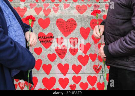 Londres, Royaume-Uni. 29th mars 2023. Deux messieurs ont apporté des fleurs à un être cher qui est malheureusement mort. Des familles, des amis, des collègues et d'autres personnes endeuillées se souvenant des victimes du coronavirus sont venus célébrer aujourd'hui l'anniversaire du mur national du Covid, organisé par les amis du mur, le long de la Tamise. Des photos de centaines de victimes sont affichées sur une longue ligne le long du mur.le mur a été créé pour la première fois en 2021 et son anniversaire est le mercredi 29th mars. Credit: Imagetraceur/Alamy Live News Banque D'Images