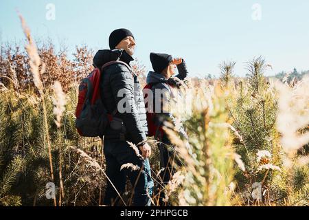 Couple explorant la nature pendant un voyage de vacances. Randonneurs avec sacs à dos sur le chemin de la montagne. Les gens qui marchent à travers l'herbe haute le long du chemin dans la prairie sur le soleil Banque D'Images