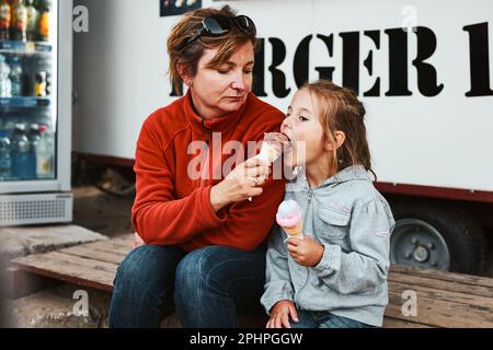 Mère et sa fille mangeant de la glace sur un passez devant le camion pendant les vacances d'été Banque D'Images