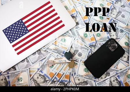 Prêt PPP. Concept du programme de protection des chèques de paie. Drapeau américain, argent avec clés, ordinateur portable et fond de téléphone. Banque D'Images