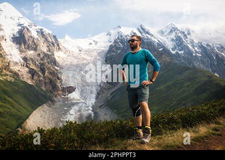 Un randonneur mâle se trouve sur une crête dans les montagnes du Caucase. Excursion en montagne. Banque D'Images