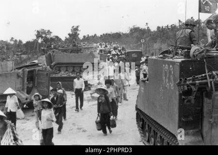 M-113 les transporteurs blindés de personnel restent près tandis que les réfugiés vietnamiens évacuent le village de My Tho, pendant l'offensive Tet. Vietnam du Sud, 1968. Photo par US signal corps) Banque D'Images