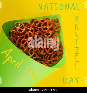 Gros plan des mini-bretzels en papier vert clair cône se trouve sur fond jaune. Concept de la journée nationale de Pretzel observé le 26 avril Banque D'Images