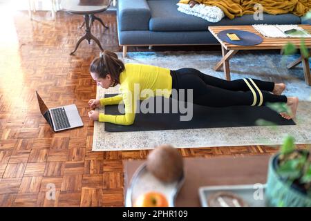 Femme faisant du plantage à la maison et regardant la formation en ligne sur Internet à l'aide d'un ordinateur portable. Banque D'Images