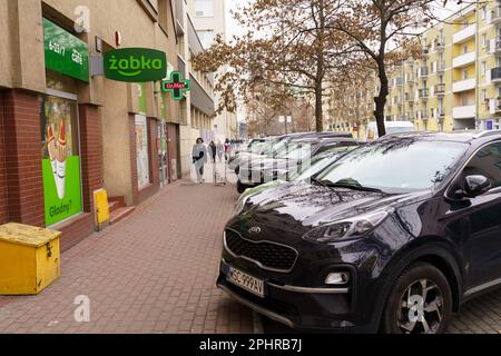 Poznan, Pologne - 20 janvier 2023 : des voitures se trouvent dans un parking dans une rue de la ville près d'un café Zabka Banque D'Images