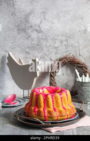 Gâteau orange à la vanille recouvert de glaçage rose, décor de Pâques. Banque D'Images