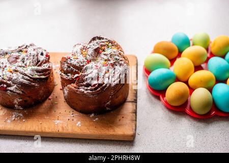 Kraffin de Pâques sur fond clair avec des œufs colorés et lumineux. Gâteau aux fruits confits, raisins secs, chocolat, noix, garniture au sucre en poudre, edibl Banque D'Images