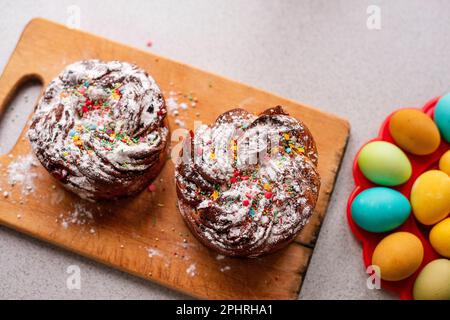 Kraffin de Pâques sur fond clair avec des œufs colorés et lumineux. Gâteau aux fruits confits, raisins secs, chocolat, noix, garniture au sucre en poudre, edibl Banque D'Images