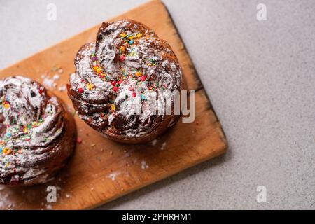 Kraffin de Pâques sur fond de bois clair. Gâteau aux fruits confits, raisins secs, chocolat, noix, garniture au sucre en poudre, décorations comestibles. Rustique Banque D'Images