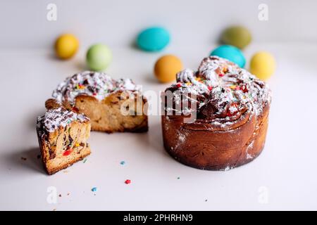 Kraffin de Pâques sur fond clair avec des œufs colorés et lumineux. Gâteau aux fruits confits, raisins secs, chocolat, noix, garniture au sucre en poudre, edibl Banque D'Images