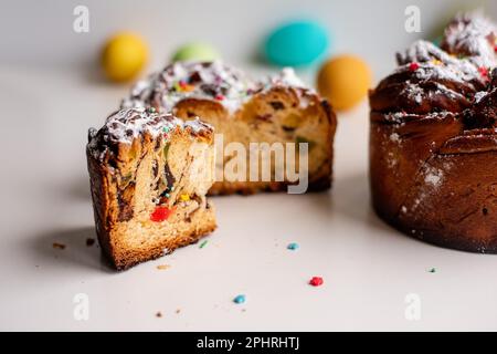 Kraffin de Pâques sur fond clair avec des œufs colorés et lumineux. Gâteau aux fruits confits, raisins secs, chocolat, noix, garniture au sucre en poudre, edibl Banque D'Images