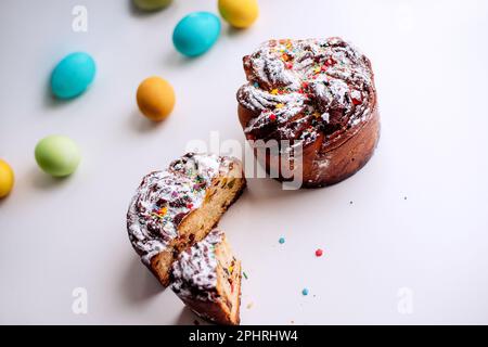 Kraffin de Pâques sur fond clair avec des œufs colorés et lumineux. Gâteau aux fruits confits, raisins secs, chocolat, noix, garniture au sucre en poudre, edibl Banque D'Images