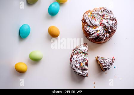 Kraffin de Pâques sur fond clair avec des œufs colorés et lumineux. Gâteau aux fruits confits, raisins secs, chocolat, noix, garniture au sucre en poudre, edibl Banque D'Images