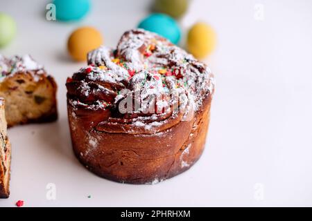 Kraffin de Pâques sur fond clair avec des œufs colorés et lumineux. Gâteau aux fruits confits, raisins secs, chocolat, noix, garniture au sucre en poudre, edibl Banque D'Images