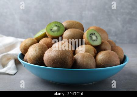 Kiwis frais mûrs dans un bol sur une table gris clair Banque D'Images