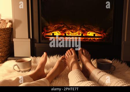 Couple se reposant près de la cheminée à la maison, près des jambes Banque D'Images