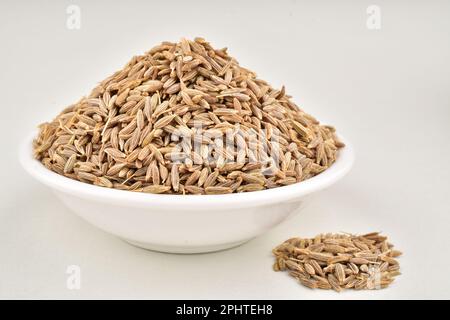 Graines de cumin dans un bol isolé sur fond blanc Banque D'Images