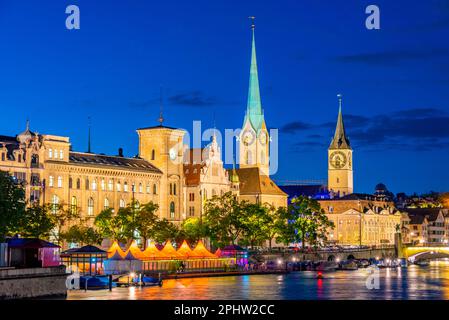 Vue sur le coucher du soleil du centre-ville historique de Zuerich avec la célèbre église Fraumuenster et la rivière Limmat par une journée ensoleillée, en Suisse. Banque D'Images
