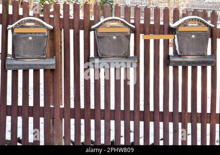 Vue sur les boîtes aux lettres en métal avec de la neige sur une clôture en bois Banque D'Images