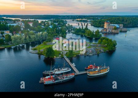 Vue sur le château d'Olavinlinna et le musée Riihisaari à Savonlinna, en Finlande, au coucher du soleil. Banque D'Images