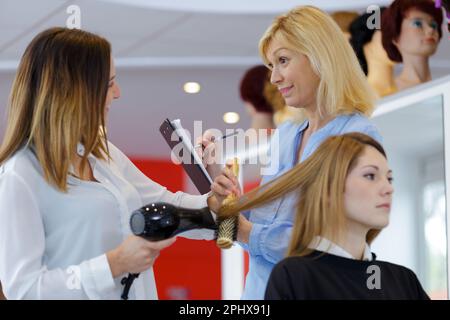 jeune coiffeur coiffeur clients séchage cheveux Banque D'Images