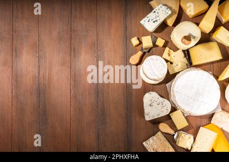 Différentes sortes de fromages. Plateau de fromages avec divers fromages, avec des raisins, des noix, un couteau à fromage et des épices, un espace de copie en bois Banque D'Images