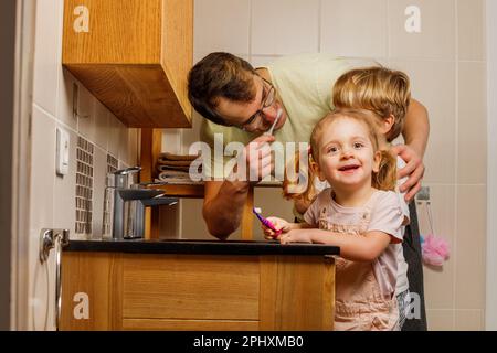 La famille brosse les dents à l'aide d'une brosse à dents dans la salle de bains avec le sourire d'une Banque D'Images