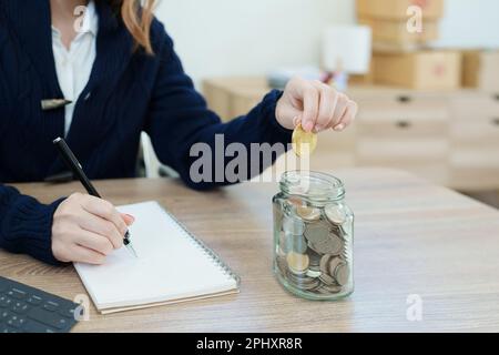 Le plan d'épargne crypto-monnaie, la jeune femme asiatique épargnant des pièces numériques dans une banque à la mode Banque D'Images