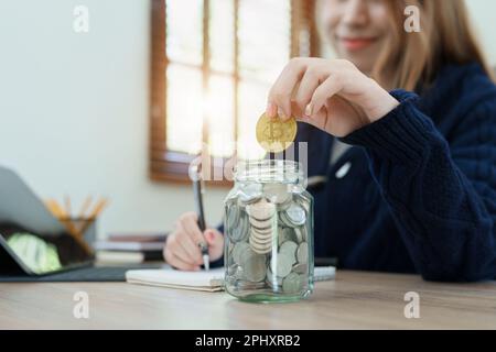 Le plan d'épargne crypto-monnaie, la jeune femme asiatique épargnant des pièces numériques dans une banque à la mode Banque D'Images