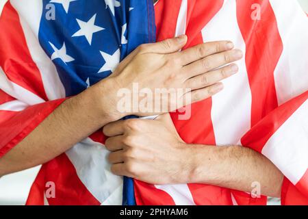Le jeune homme priant en nous portant le drapeau en mettant la main sur le coeur - concept de contemplation et de liberté. Banque D'Images