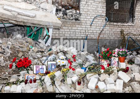 Des photos des morts, des bougies commémoratives et des fleurs sur la scène de la mort des résidents de la maison détruite peuvent être vues à Izyum. Izyum dans la région de Kharkiv en Ukraine, six mois après le retrait de l'armée russe. Bien que la ville ne soit plus en feu, il existe encore un risque élevé d'explosions dues à la présence de mines, de câbles trip et de munitions non explosées. Izyum a été libéré le 10 septembre 2022 lors d'une contre-offensive des forces armées ukrainiennes, mais la ville a été gravement endommagée par les bombardements et l'occupation russes, avec 80% des bâtiments endommagés. Tombes massives d'ukrainien Banque D'Images