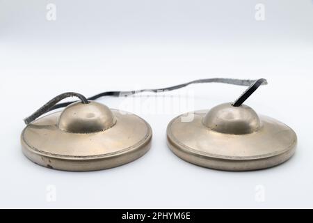 Tingsha bouddhiste tibétaine (cymbales tibétains) avec bracelet en cuir isolé sur blanc Banque D'Images