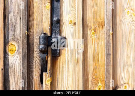 Anciens raccords de charnière noirs fabriqués par un forgeron. Raccords installés sur une ancienne porte en bois d'un ancien hangar Banque D'Images