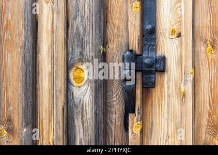 Anciens raccords de charnière noirs fabriqués par un forgeron. Raccords installés sur une ancienne porte en bois d'un ancien hangar Banque D'Images