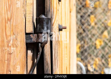 Anciens raccords de charnière noirs fabriqués par un forgeron. Raccords installés sur une ancienne porte en bois d'un ancien hangar Banque D'Images