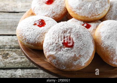 Délicieux beignets avec gelée et sucre en poudre sur un présentoir à pâtisseries en bois, gros plan Banque D'Images