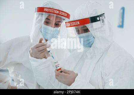 Les travailleuses médicales en uniforme de protection travaillent sur le vaccin COVID-19 Banque D'Images