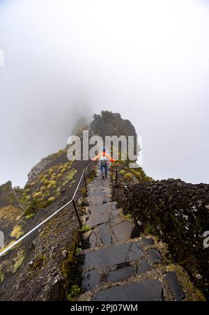 Randonneurs dans la brume, randonnée de Pico Arieiro à Pico Ruivo, sentier étroit exposé sur la falaise rocheuse, montagnes centrales de Madère, Madère, Portugal Banque D'Images