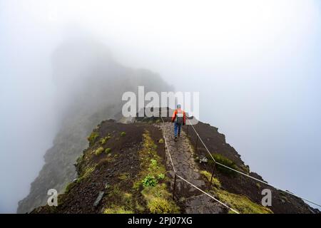 Randonneurs dans la brume, randonnée de Pico Arieiro à Pico Ruivo, sentier étroit exposé sur la falaise rocheuse, montagnes centrales de Madère, Madère, Portugal Banque D'Images