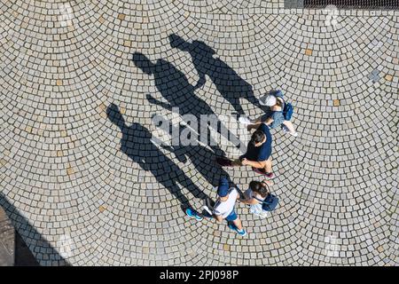 Vue panoramique de quatre personnes, une famille traversant une place pavée, ombre, photo de symbole, Stuttgart, Baden-Wuerttemberg, Allemagne Banque D'Images