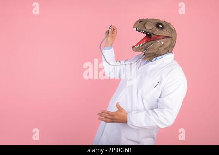 Médecin avec tête T Rex tenant un stéthoscope sur fond rose corail isolé Banque D'Images