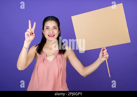 une jeune femme adulte tient une bannière dans sa main pour faire le symbole de paix et d'amour Banque D'Images