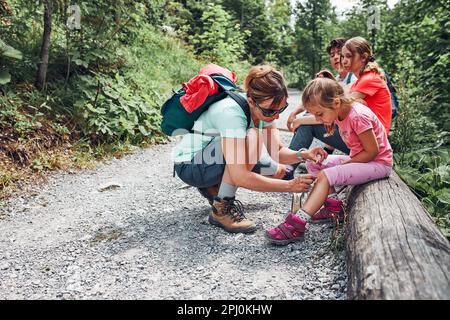 Mère portant la plaie sur le genou de sa petite fille avec un médicament en spray. Un accident s'est produit lors d'un voyage de vacances d'été en famille. Les gens activement Banque D'Images