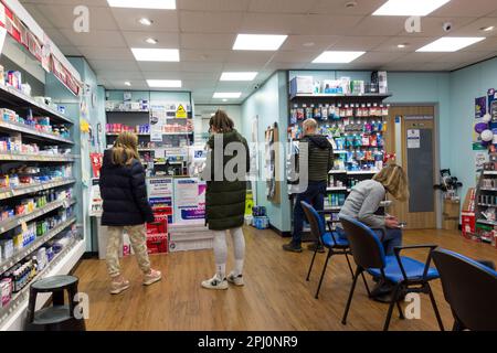 Clients en file d'attente à l'intérieur du pharmacien, Royaume-Uni Banque D'Images