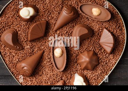 Bonbons au chocolat en grains de chocolat dans une boîte en coeur sur fond de bois foncé vue rapprochée du dessus, Saint-Valentin. Banque D'Images